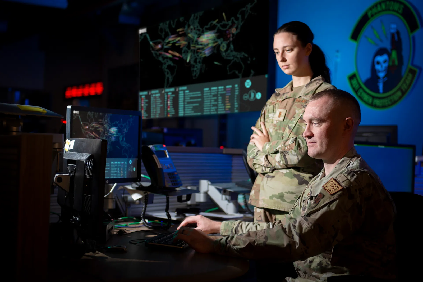 Two service members monitoring cyber operations displays